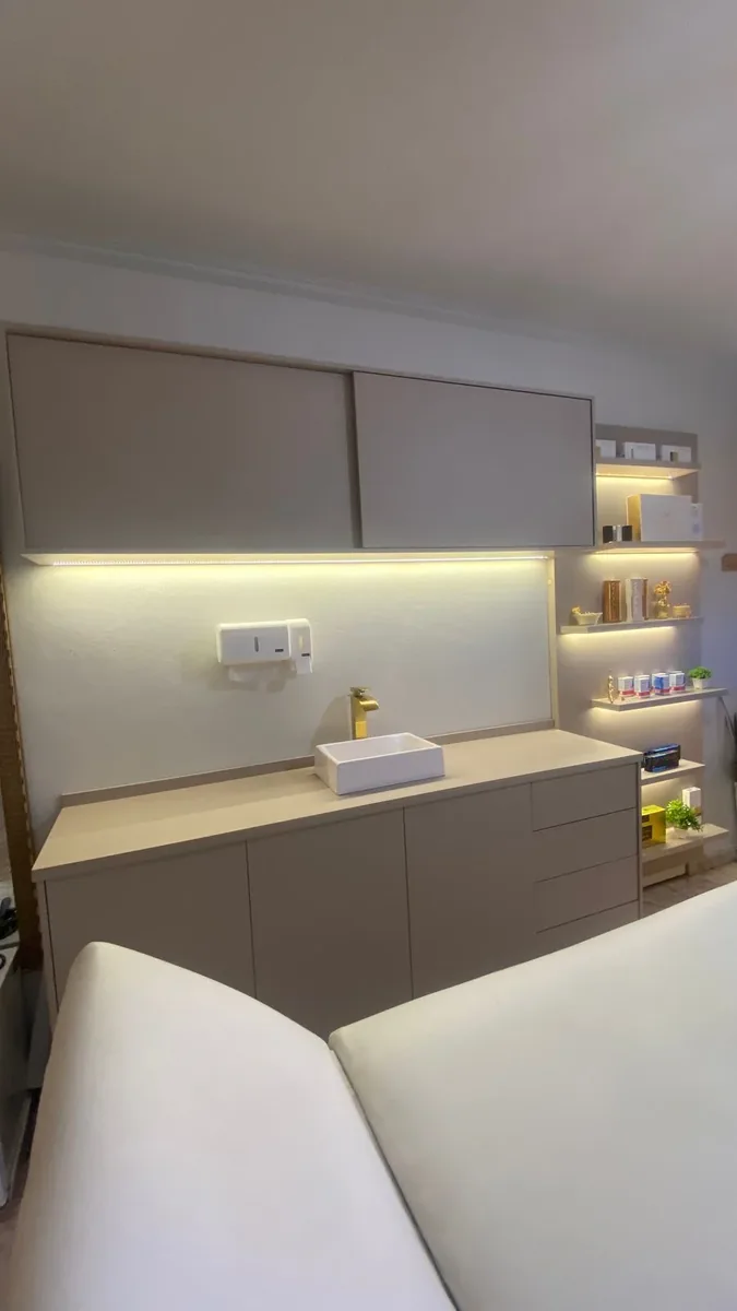Sala de procedimentos com armários, pia e torneira dourada
